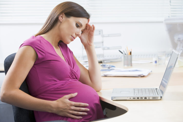 Pregnant woman at work with laptop looking stressed Maternity Leave